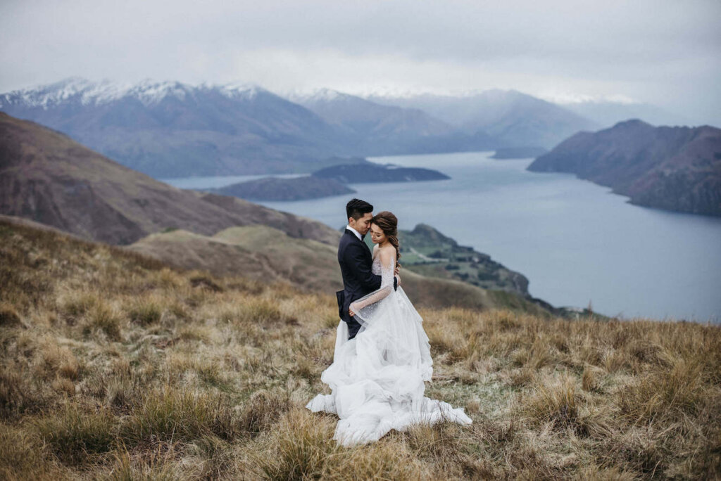 Couple in wedding dress and tux posing in front of mountainscape