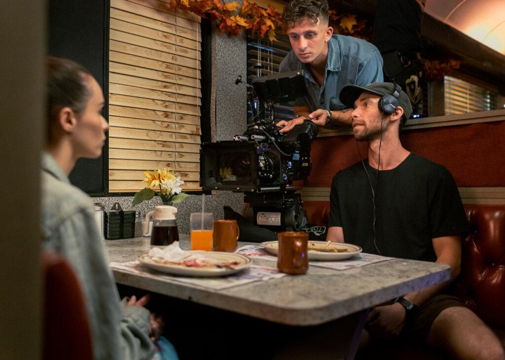 Gian Carlo Stigliano on set in a diner with actress and crew member