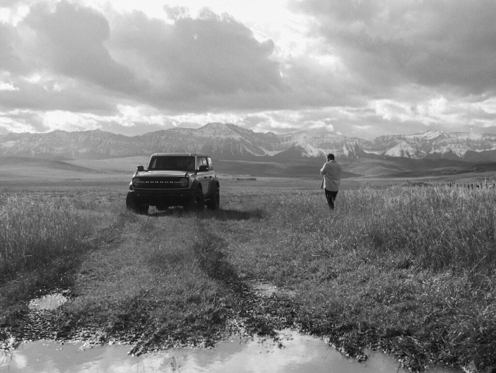 Alexander McInnes taking photo of Ford Bronco in front of mountainscape