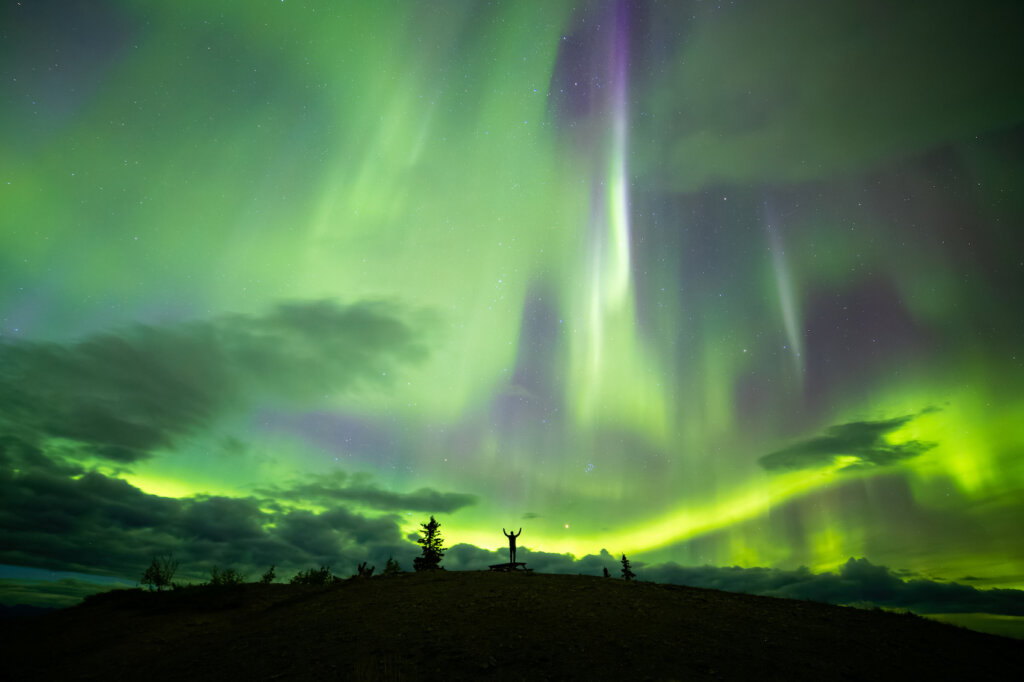 Alex Armitage standing in front of the northern lights