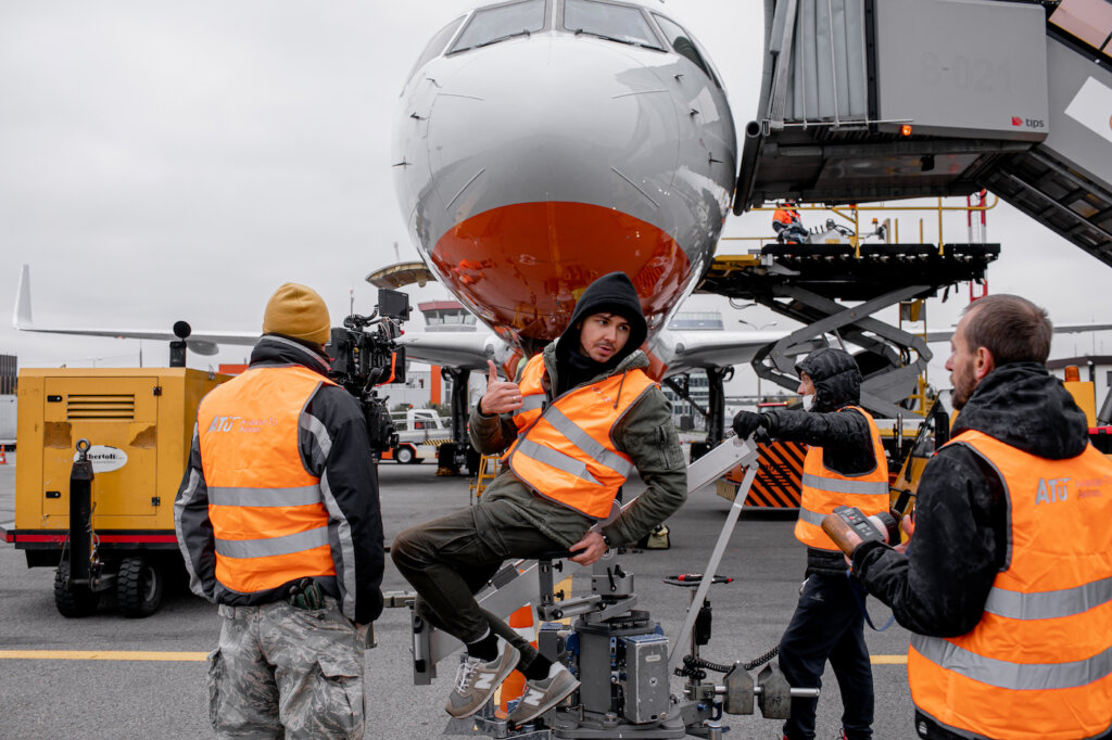 Andrew Beresnev filming on airplane runway in front of airplane